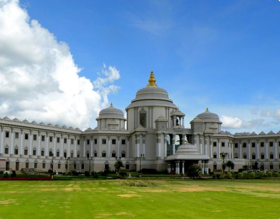 A large government building in India with domes, set behind a green lawn